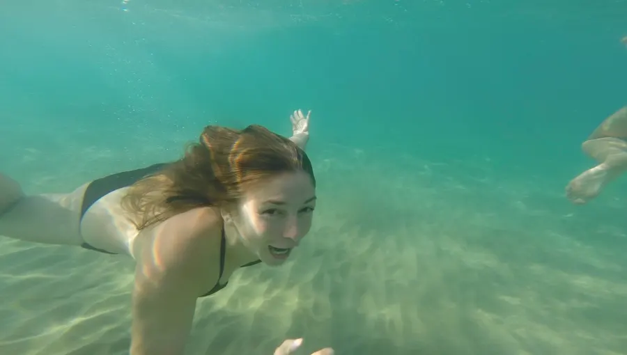 A woman swims underwater in turquoise sea